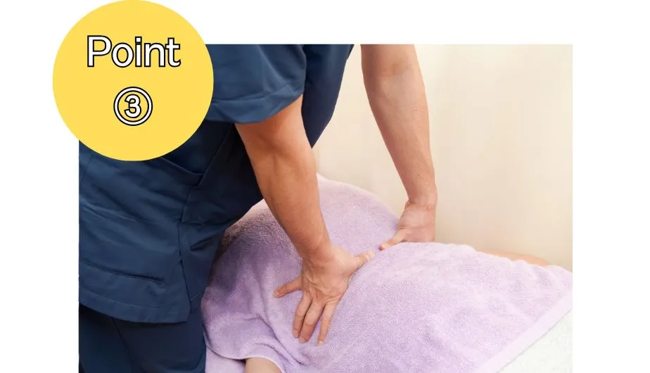 施術ベッドでうつ伏せの人の背中を、施術者が両手で押圧している様子(Point③)